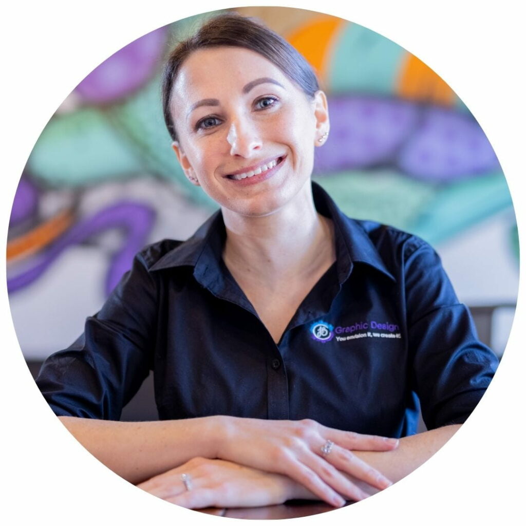 woman smiles with her arms crossed on the table in front of her