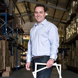 man stand in a warehouse holding picture frames